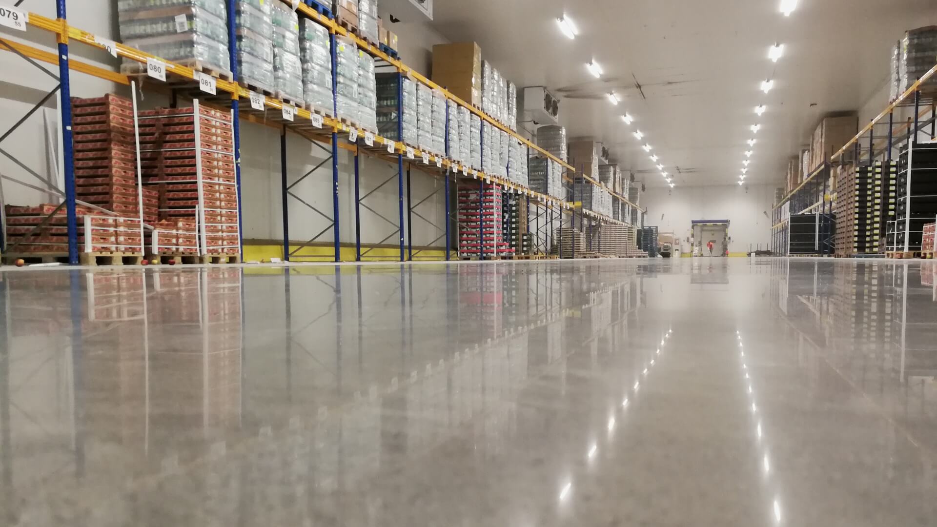 Wypolerowana posadzka betonowa centrum dystrybucyjnego Netto po renowacji systemem Silicol Renova — alejka magazynowa